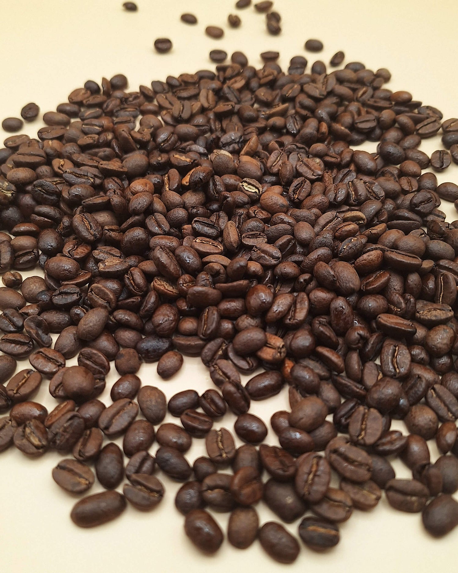 Roasted arabica coffee beans on a beige background.