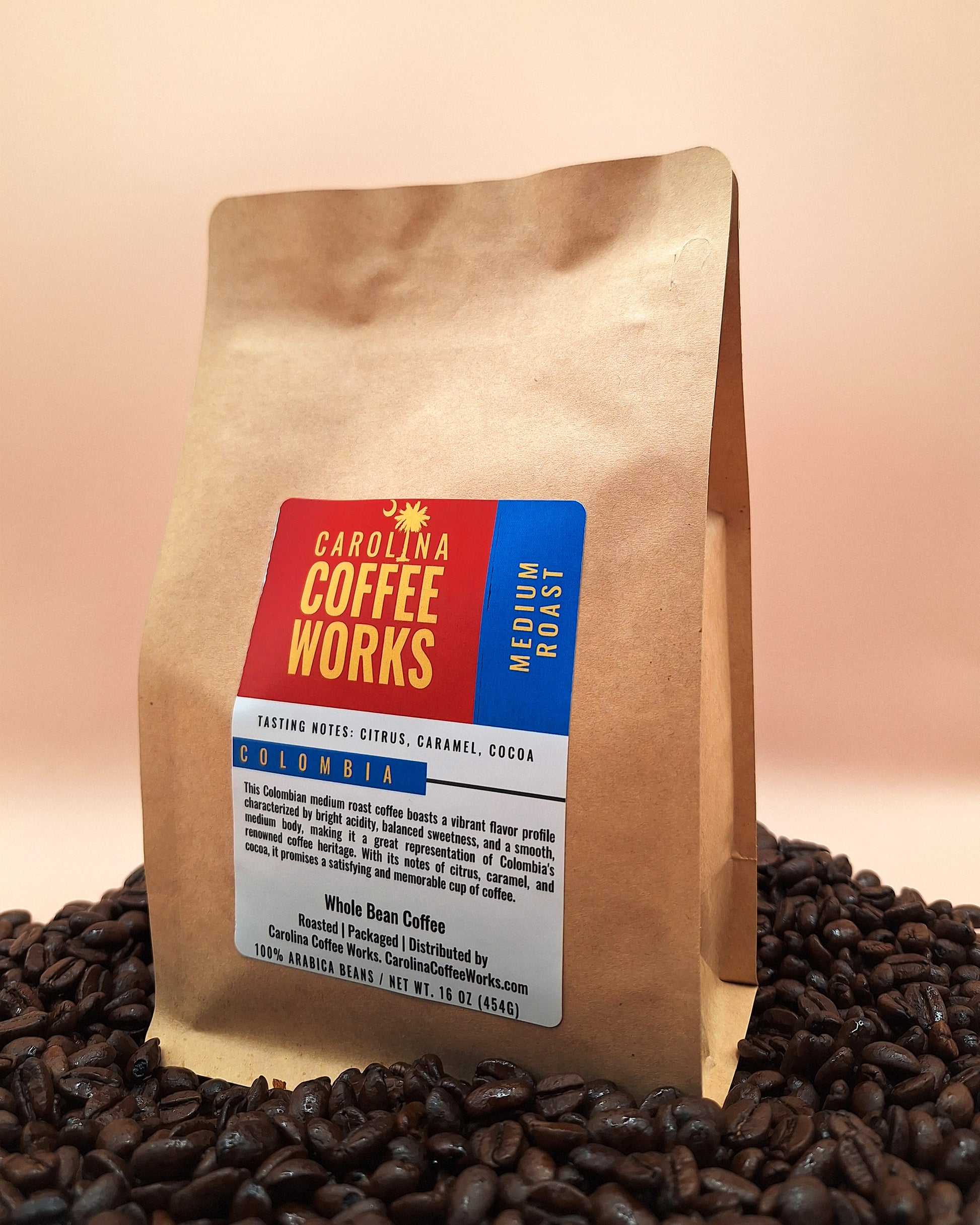 A brown paper bag of Carolina Coffee works colombian medium roast, sitting on a pile of Colombian supremo coffee beans