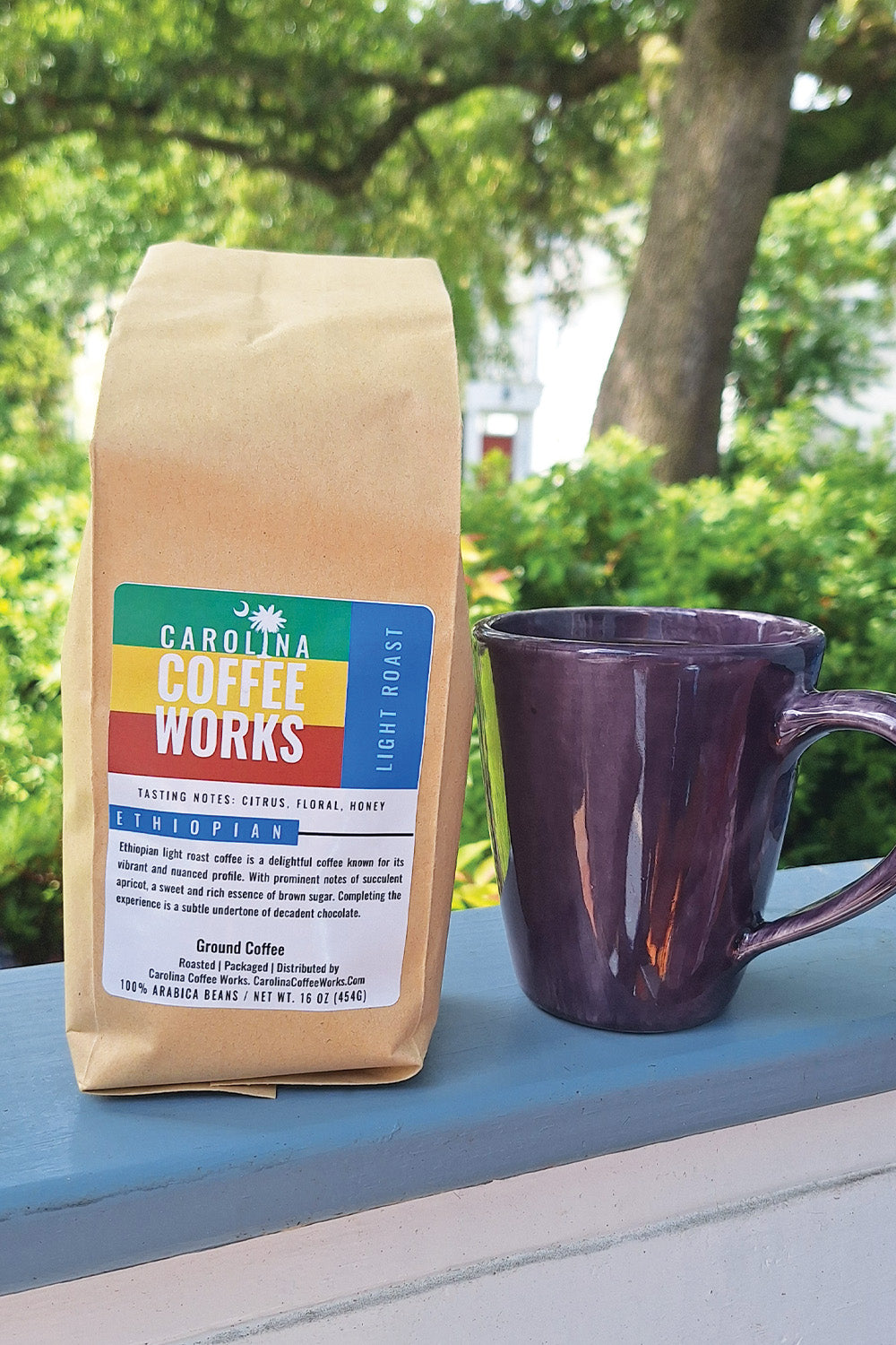 A bag of Ethiopian light roast coffee by Carolina Coffee Works sitting outside next to a cup of coffee.