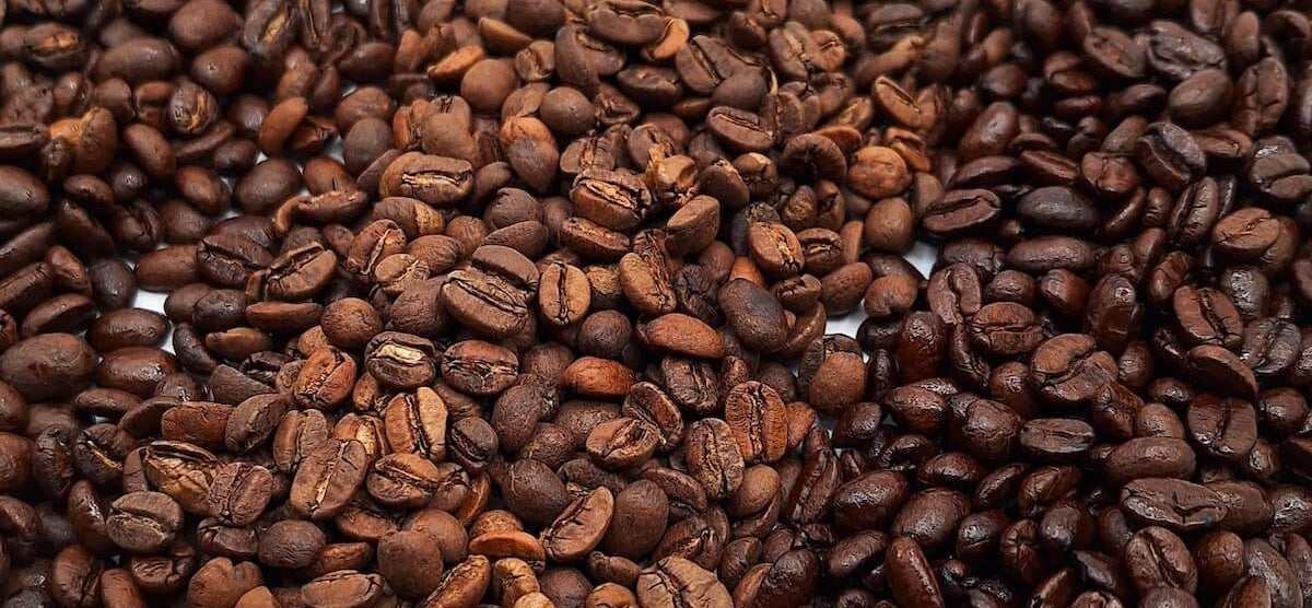 A variety of roasted arabica whole coffee beans, in light, medium and dark roasts.